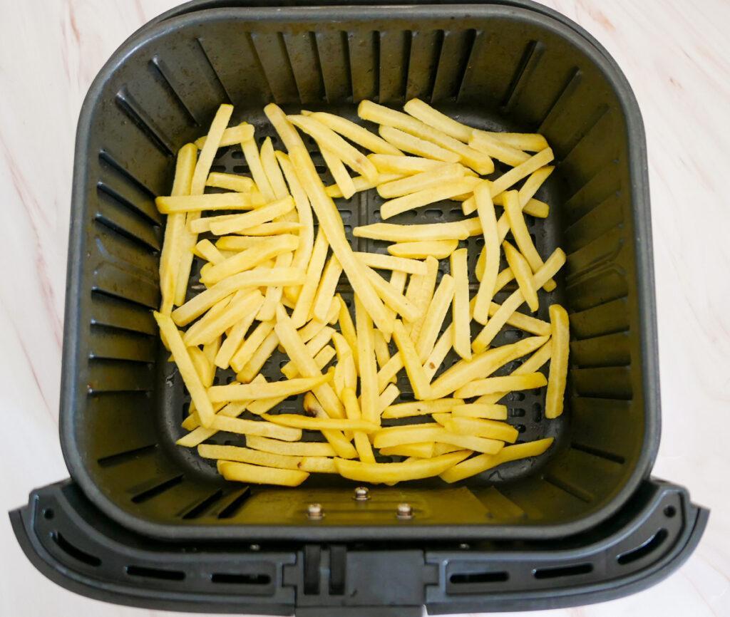 Frozen French Fries in a single layer on air fryer basket - Cook Simply
