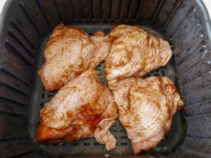 adding chicken thighs in a single layer to air fryer basket - cook simply