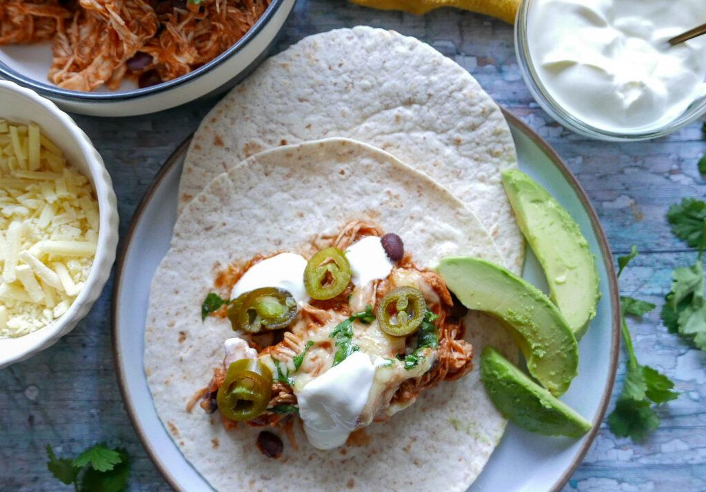 Serving chicken enchilada filling with tortilla and sliced avocados - Cook Simply